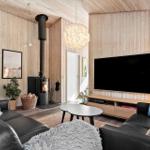 Wohnzimmer mit Holzwand, Kaminofen, Sofa und Fernseher.