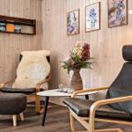 Zwei Sessel mit Felldecke und Beistelltisch in Holzvertäfelung.