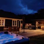 Hochwertige Außenausstattung mit Whirlpool, Grill und Sitzgelegenheiten bei Nacht.
