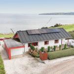 Wohnhaus mit Solaranlage am Wasser, umgeben von Grünflächen und einem kleinen Garten.