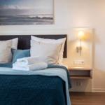 Schlafzimmer mit Bett, Nachttisch und Wandbild. Handtuch auf Bett.