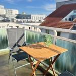 Terrasse mit Tisch, Stuhl und Pflanze. Blick auf Dächer und Gebäude.