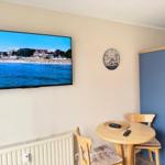 Wohnraum mit TV, runden Tisch und blauem Schrank an der Wand.