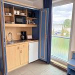 Küche mit Kühlschrank, Mikrowelle und Fenster zum Balkon.