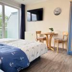 Schlafzimmer mit Bett, TV, Tisch und Stühlen sowie Balkontür.