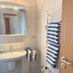 Badezimmer mit Waschbecken, Spiegel und Handtüchern auf Heizung