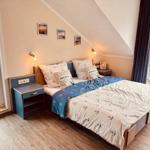 Schlafzimmer mit Dachschrägen, Bett mit Ankern, Nachttische und Balkonansicht.