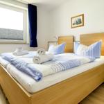 Bedroom with bed, window, and wooden floor. Double bed with blue-white bedding.