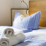 Room with bed, pillows, and rolled towels