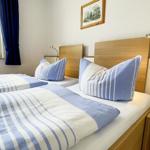 Two single beds with blue and white bedding and wooden frames. Window with blue curtains.