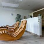 Living area with wooden loungers and sauna in the background.