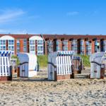 Beach with beach chairs and sea view of vacation apartments.
