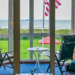 Terrace with two chairs and table, view of beach and sea.