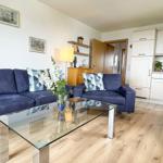 Living room with sofa, couch and glass table. Kitchen with white cabinets and dining table.