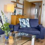 Living room with blue sofa, glass table, and kitchen area.