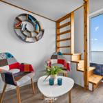 Zimmer mit Blick auf Wasser, zwei Stühle, Tisch und Bücherregal an der Wand.