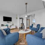 Wohnzimmer mit blauen Sesseln, Kamin und Fernseher an der Wand.