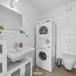 Badezimmer mit Waschmaschine, Trockner, Toilette und Spiegel.
