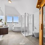 Badezimmer mit Badewanne, Dusche und Sauna. Fenster mit Blick auf Wasser.