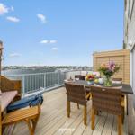 Terrasse mit Sitzgelegenheiten und Meerblick. Tisch mit Blumen und Obst.