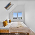 Schlafzimmer mit Dachfenster und Blick auf Wasser.