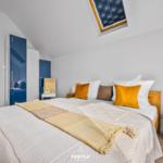 Schlafzimmer mit Blick auf Wasser, Dachfenster und blauer Schrank.