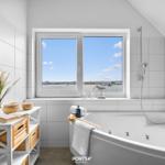 Badezimmer mit Badewanne und Blick auf Wasser