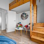 Höhlenwohnung mit Holztreppe, Sitzbereich und Bücherregal.
