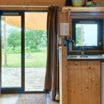 Küche mit Fenster und Glastür zum Garten. Holzwände und Küchenschränke.