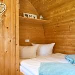 Schlafzimmer mit Holzwand, Bett mit weißen Kissen und blauen Handtüchern.