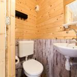 Bad mit Toilette und Waschbecken, Holzwände und Spiegel.