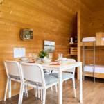 Ein Raum mit Esstisch, Stühlen und Kojenbetten an der Wand.