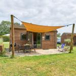 Holzhaus mit Terrasse, Sonnensegel und Gartenmöbeln.