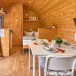 Wohnraum mit Esstisch, Bett und Küchenbereich in Holzhaus.