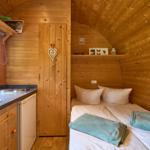 Kleines Schlafzimmer mit Bett, Küchenzeile und Holzwand.