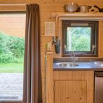 Küche mit Spüle, Herd und Kühlschrank. Draußen liegt ein Terrassenbereich mit Stuhl.