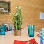 Tisch mit Blumen, Gläsern und roten Servietten in rustikaler Holzwand