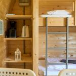 Hochbett mit Leiter und Küchenzeile mit Kaffeemaschine und Wasserkocher.