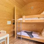 Zimmer mit Doppelstockbett, Esstisch und Holzwand.