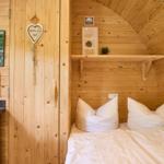 Schlafzimmer mit Bett, Holzwand und Küchenzeile.