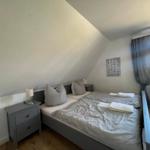 Schlafzimmer mit Doppelbett, Nachttisch und Fenster.