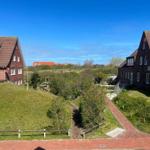 Zwei Häuser mit rotem Dach und grünem Grundstück unter blauem Himmel.