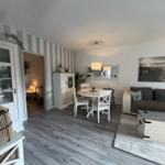 Wohn- und Essbereich mit Sofa, Esstisch und Wandbild.