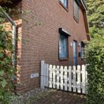 Rotes Backsteinhaus mit blauen Fenstern und weißem Zaun. Privatgeheimniszeichen angebracht.