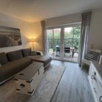 Wohnzimmer mit Sofa, Fernseher und Terrasse.