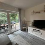 Wohnzimmer mit TV-Schrank, Terrasse und Gartenansicht.