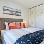 Schlafzimmer mit Doppelbett, weißen Nachttischen und großen Schränken.