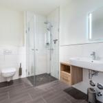 Badezimmer mit Dusche, Waschbecken und Toilette.