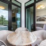 Terrasse mit runden Tisch und weißen Stühlen. Blick in Wohnzimmer und Schlafzimmer.