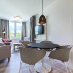 Wohnbereich mit Essplatz, TV und Schlafzimmer mit Bett und Kissen.